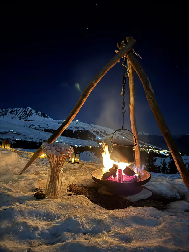 Campfire tripod with a hanging cauldron, in the snow under the stars