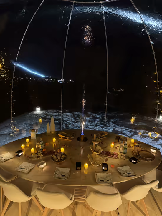 A candlelit round table set inside a transparent bubble, at night
