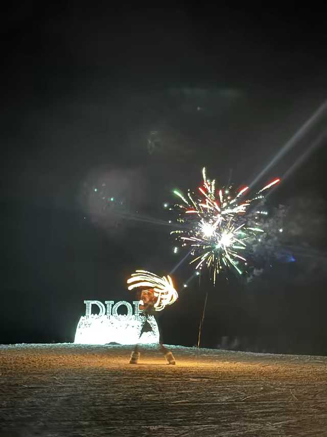 Fire performer and fireworks beside an ice sculpture on a snowy mountain