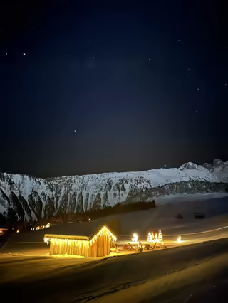 Wooden chalet glowing with lights under a starry sky, in the mountains of Savoie