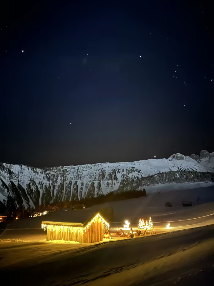 Wooden chalet glowing with lights under a starry sky, in the mountains of Savoie