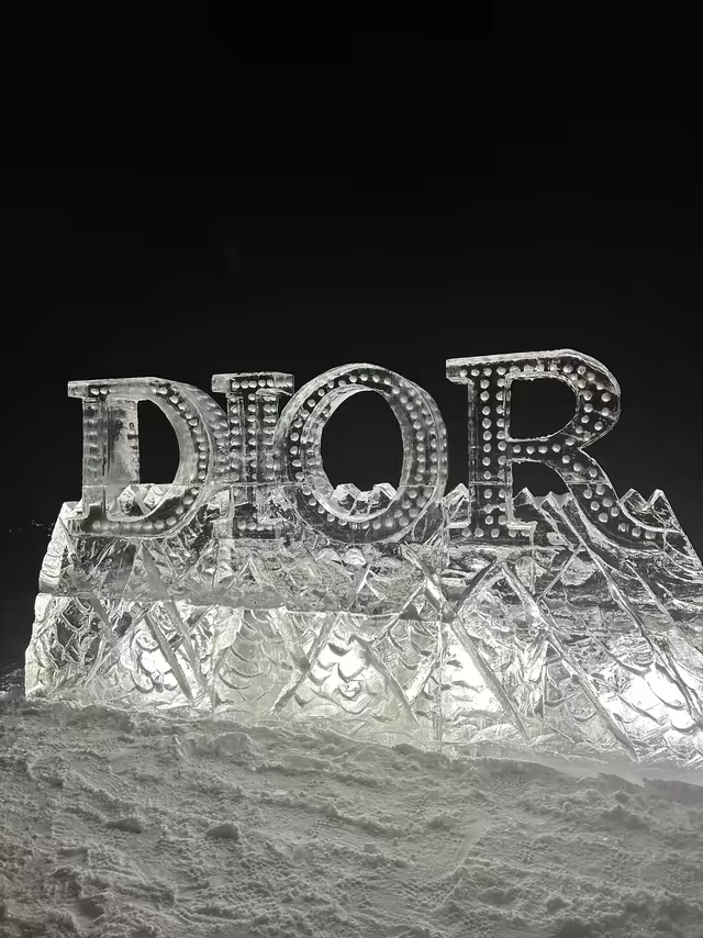 An illuminated ice sculpture on a snowy summit at night