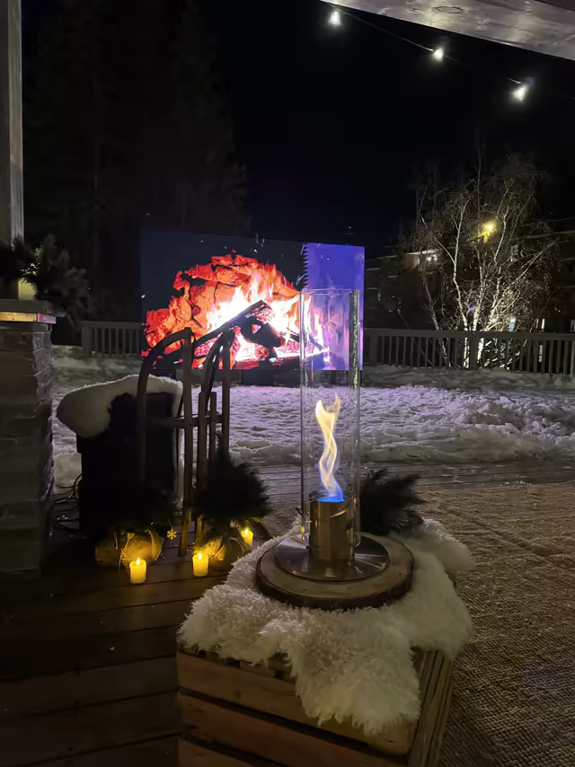 Terrace with a fireplace screen, flame lamps and candles on a winter evening