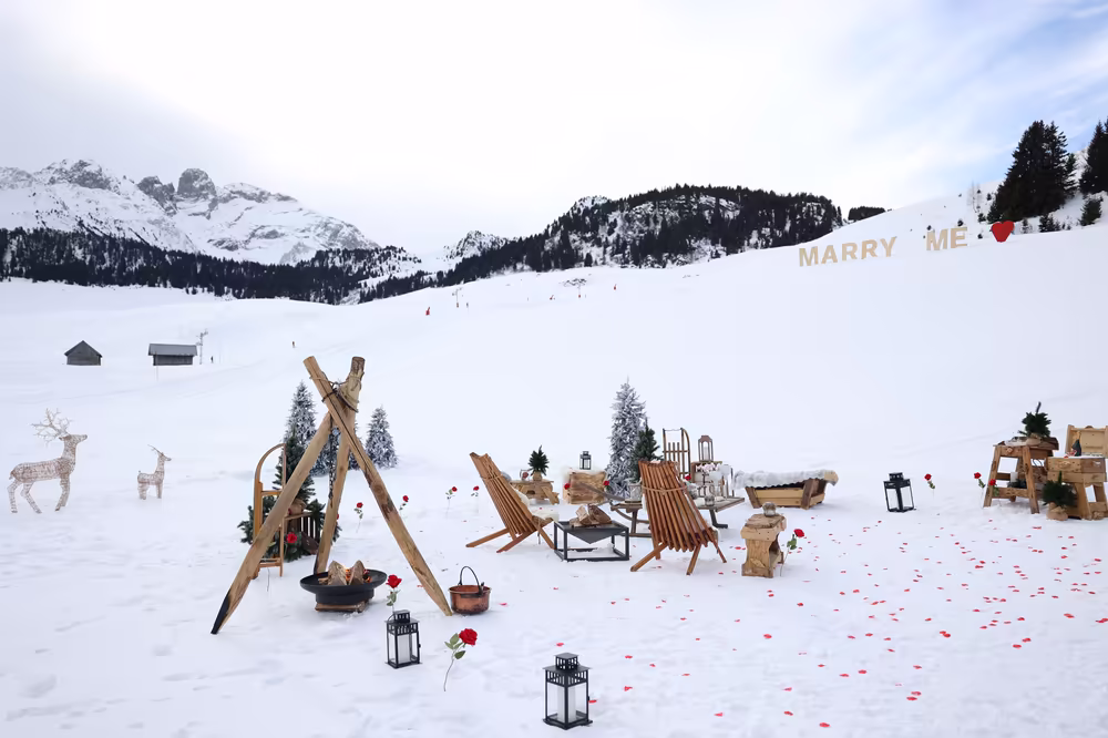 The whole setting on the snowfield: tripod, deck chairs, lanterns and rose petals, the Marry Me letters on the slope