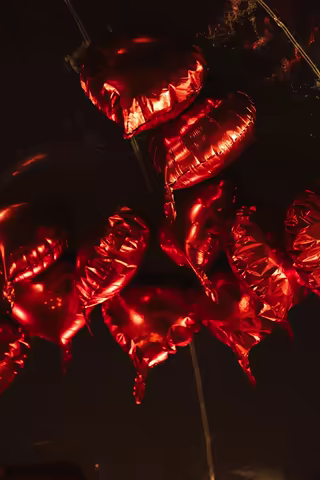 Red heart-shaped balloons floating in the night
