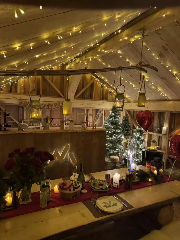 Table of red roses and candles under fairy lights in a wooden barn, a heart balloon above